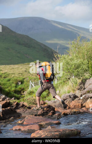 Man crossing a river on a hike Stock Photo