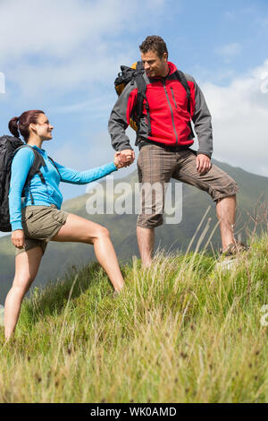 Handsome hiker helping his girlfriend uphill Stock Photo