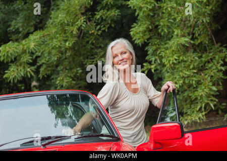 Cheerful mature woman getting off her convertible Stock Photo