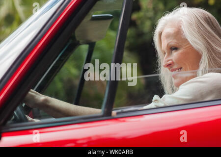 Cheerful mature woman driving red convertible Stock Photo