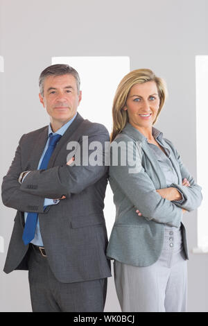 Two content businesspeople looking at camera standing back-to-back Stock Photo