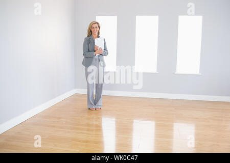 Joyful realtor standing in a room holding documents Stock Photo