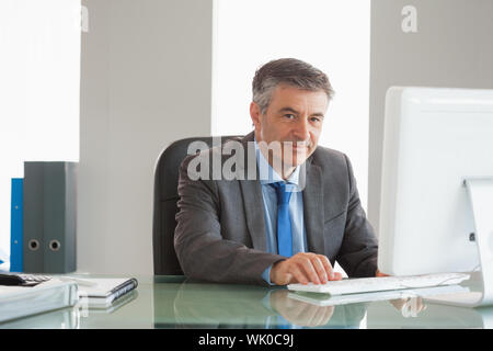 Smiling businessman using computer at office Stock Photo