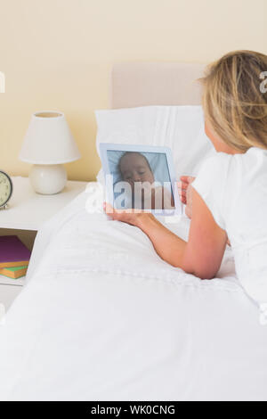 Attentive woman using a tablet pc lying on her bed Stock Photo