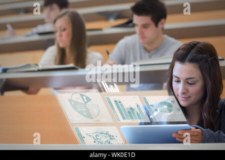 Student using tablet pc to take notes in lecture hall Stock Photo
