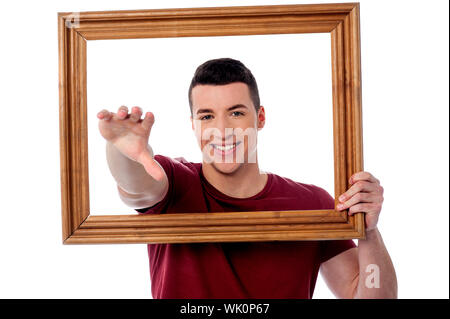 Young man getting out of his hand from the picture frame Stock Photo