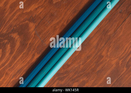 three colored pencils on wooden desk in isolated background, diagonal view Stock Photo
