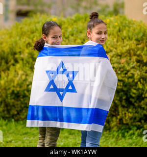 Two patriot jewish teenager girl standing and enjoying with the flag of Israel on nature background. Election, Yom Hazikaron, patriotic holiday Independence day Israel - Yom Ha'atzmaut concept. Stock Photo