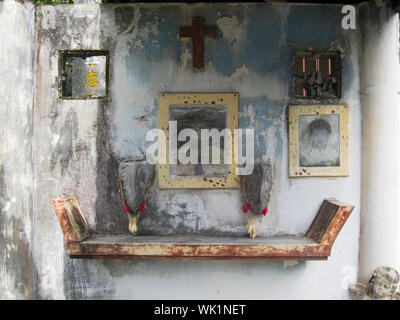 The altar area inside a typical mausoleum at the Chinese North Cemetery in Manila, Philippines. Pictures of the departed are on the wall above the tom Stock Photo