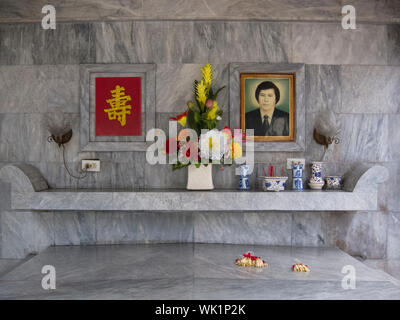 The altar area inside a typical mausoleum at the Chinese North Cemetery in Manila, Philippines. Pictures of the departed are on the wall above the tom Stock Photo