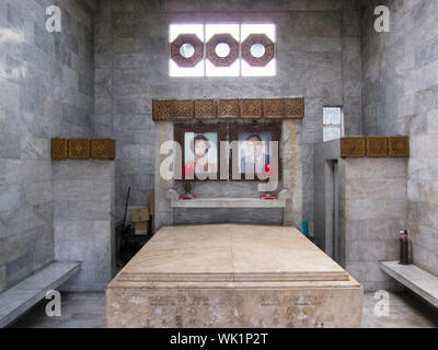 The altar area inside a typical mausoleum at the Chinese North Cemetery in Manila, Philippines. Pictures of the departed are on the wall above the tom Stock Photo