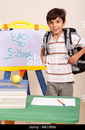 Schoolboy with books and backpack in a classroom enviroment Stock Photo