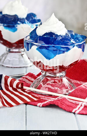 Gelatin layered dessert of cubes of red and blue jello with white flufy whipped cream for the Fourth of July holiday. Shallow depth of field. Stock Photo