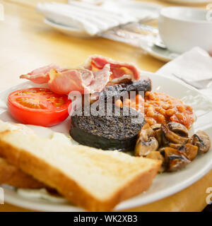 Plate with Full Scottish breakfast containing  toasts, fried eggs, baked beans, grilled black pudding, sausage, tomato,  mushrooms and bacon Stock Photo