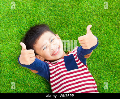 smiling kid lying and thumb up  on a meadow Stock Photo
