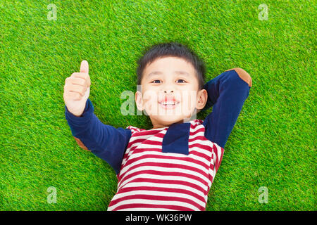 happy kid lying and raise his thumb  on a meadow Stock Photo