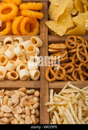 Various snacks in vintage wooden box. Onion rings,nachos, salty peanuts with potato sticks and pretzels. Suitable for beer and fizzy drinks. Stock Photo