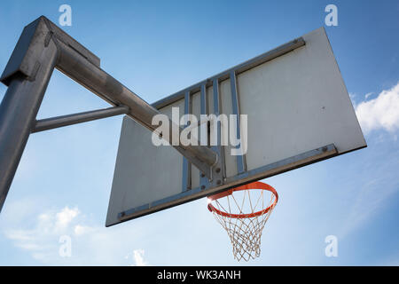 Basketball hoop against  lovely blue summer sky with some fluffy white clouds Stock Photo