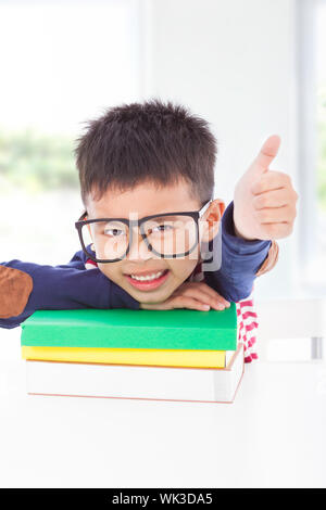 little boy lying on books and thumb up Stock Photo