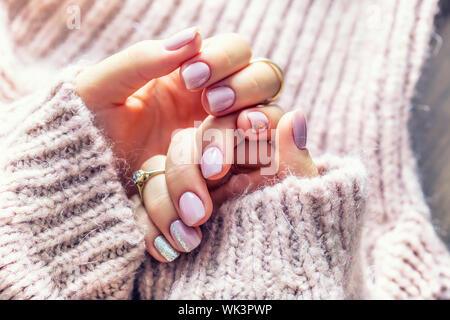 Art nail manicure for bride in purple sweater. Gel nails in soft pink color Stock Photo