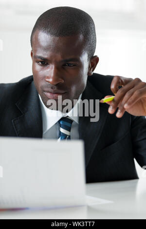 young adult afro-american businessman examining documents indoors Stock Photo