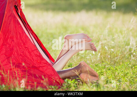 young multiethnic couple lying in tent with feet crossed. Copy space Stock Photo