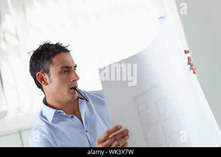 portrait of mid adult architect reading blueprint and smiling Stock Photo