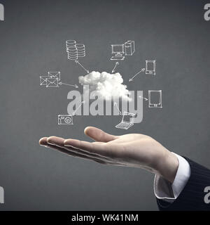 Hand drawn technology and computer icons around cloud with hand on gray background, cloud computing concept. Stock Photo