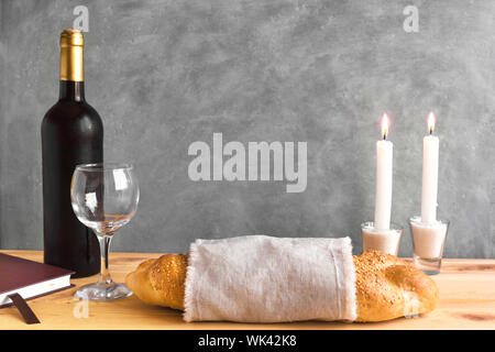 Shabbat or Shabath concept. Challah bread, shabbat wine, book and candles, copy space. Traditional Jewish Shabbat ritual. Shabbat Shalom. Stock Photo
