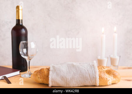 Shabbat or Shabath concept. Challah bread, shabbat wine, book and candles, copy space. Traditional Jewish Shabbat ritual. Shabbat Shalom. Stock Photo