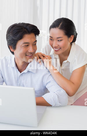Happy couple using laptop together at home in the living room Stock Photo