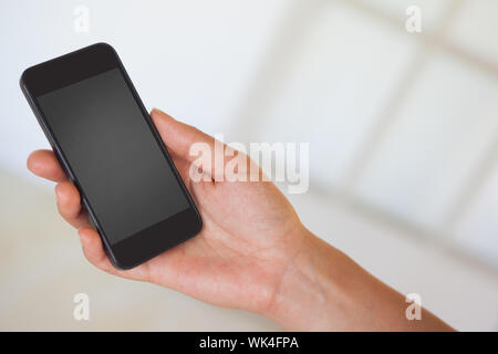 Womans hand holding black smartphone in a bright room Stock Photo