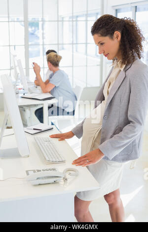 Pregnant casual businesswoman using computer in the office Stock Photo