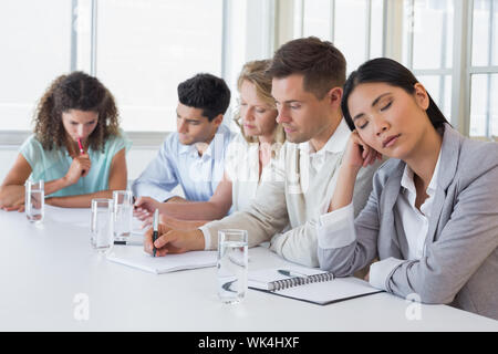 Casual businesswoman falling asleep during meeting in the office Stock Photo