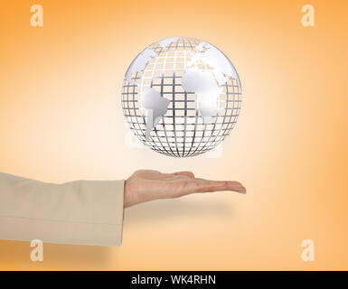 Female hand presenting silver globe against orange vignette Stock Photo