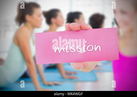 Fit blonde holding card saying mission against yoga class in gym Stock Photo