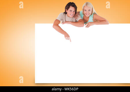Composite image of attractive couple showing white card Stock Photo