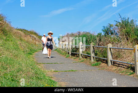 An elderly couple making their way down to the beach from the west cliffs at Mundesley, Norfolk, England, United Kingdom, Europe. Stock Photo