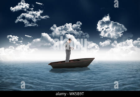 Composite image of standing businessman typing on his laptop in a sailboat in open sea Stock Photo