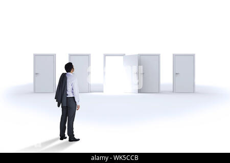 Businessman standing against door opening revealing bright light Stock Photo