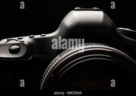 Professional modern DSLR camera low key image - Modern DSLR camera with a very wide aperture lens on Stock Photo