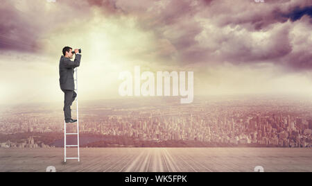 Businessman standing on ladder against balcony overlooking city Stock Photo