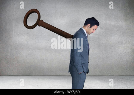 Composite image of wound up businessman with hands in pockets against grey room Stock Photo