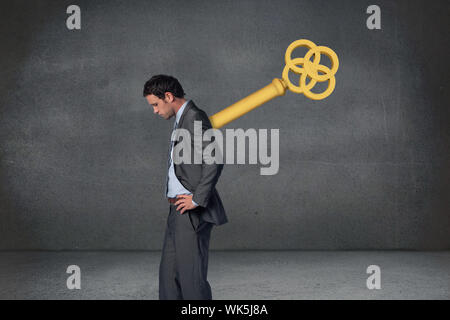 Composite image of wound up businessman with hands on hips against grey room Stock Photo