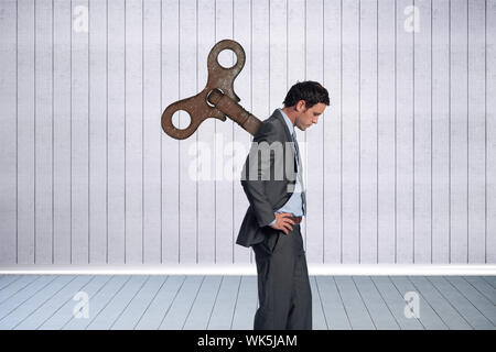 Composite image of wound up businessman with hands on hips against grey room Stock Photo