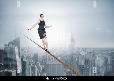 Composite image of businesswoman doing a balancing act against cityscape Stock Photo