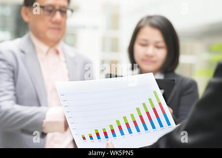 Asian business team meeting. Young business executive presenting charts to CEO boss over office. Stock Photo