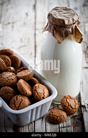 meringue almond cookies in a bowl and bottle of milk on wooden background Stock Photo