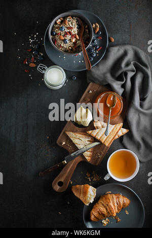 Breakfast served with oatmeal and fruits, croissants, jam and butter. Delicious healthy breakfast. Stock Photo
