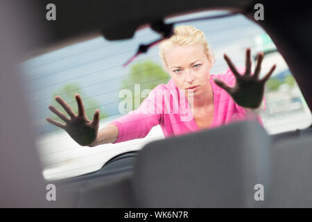 Self-sufficient, strong, young woman pushing a car. Engine breakdown. Stock Photo